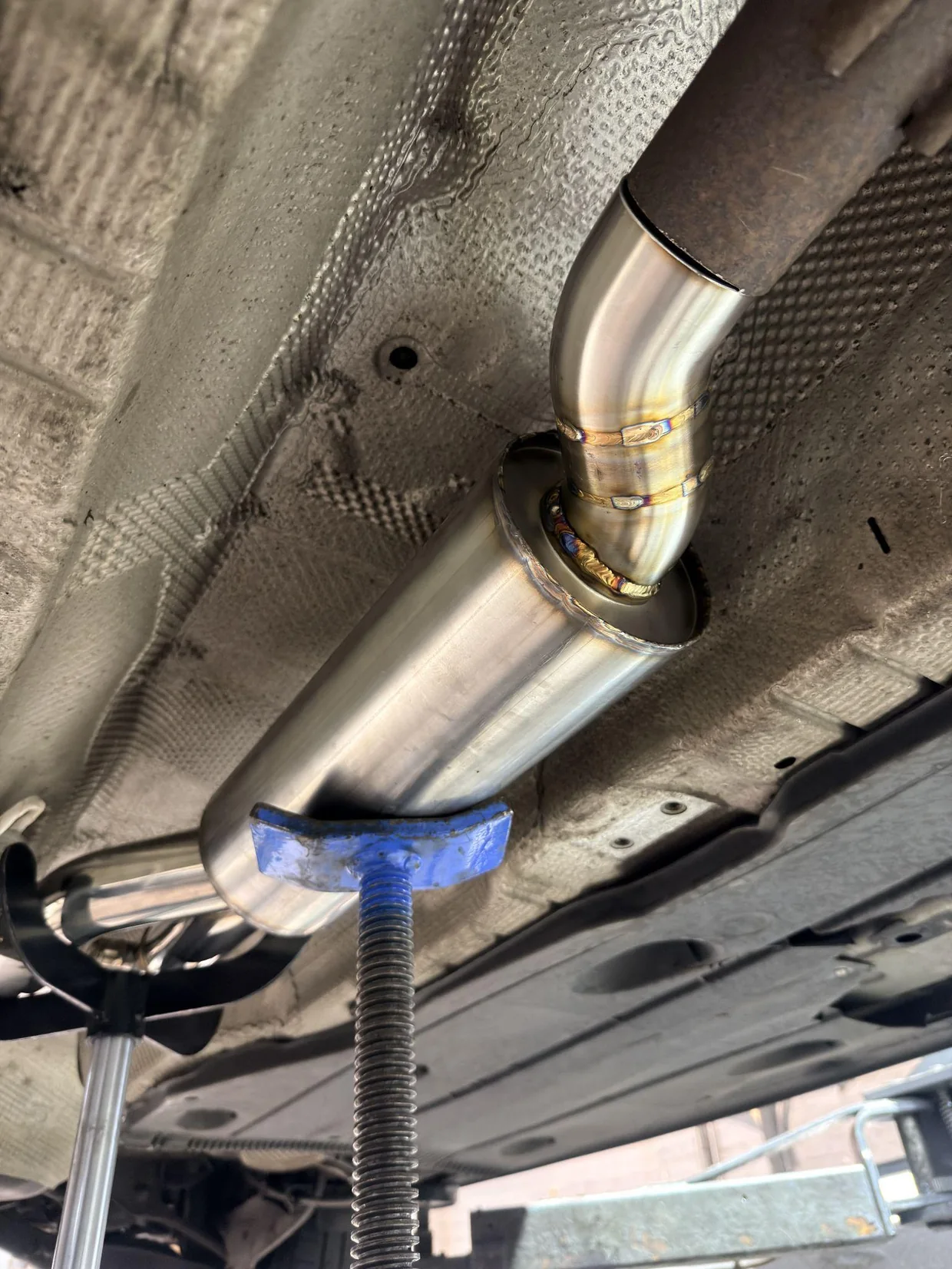 Custom stainless steel exhaust mid-section being fitted beneath the SEAT Leon Cupra 290 at Pi Motorsport